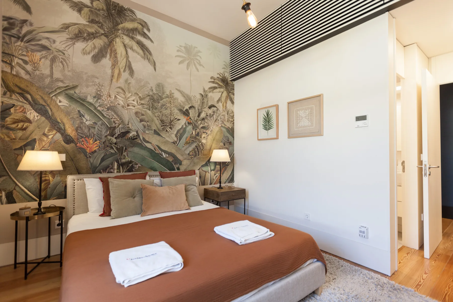 Un dormitorio con una cama bajo un mural tropical.