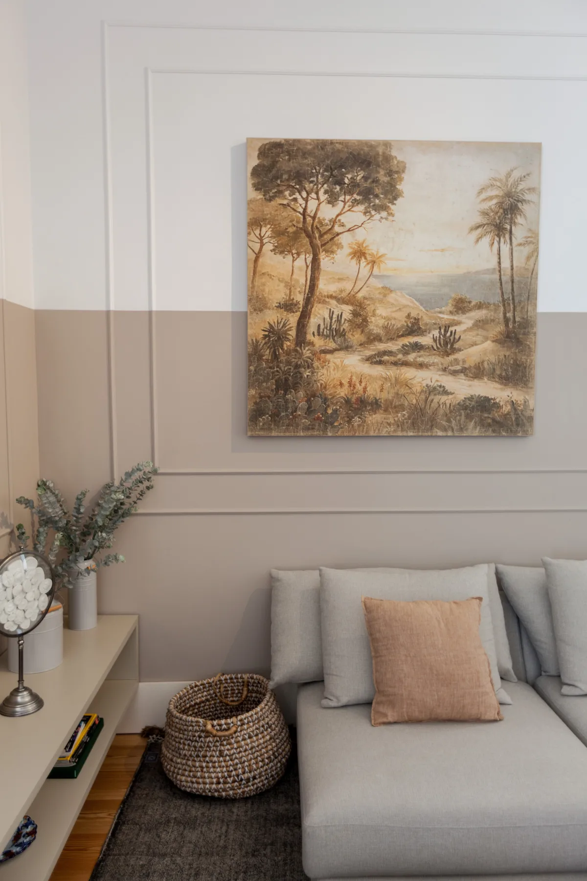 Sala de estar con asientos grises, un cuadro decorativo y una cesta tejida.