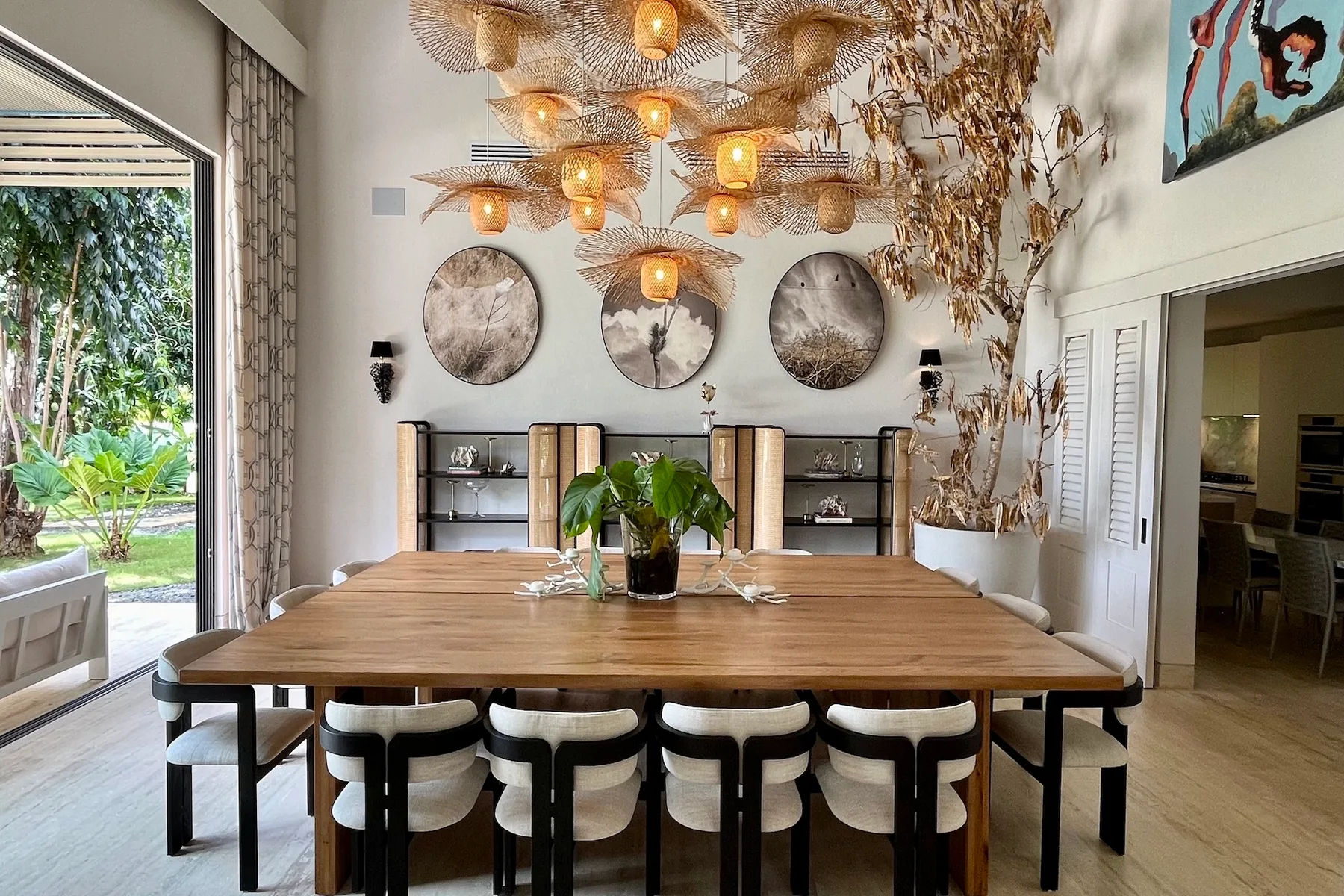 Comedor con una larga mesa de madera y lámparas tejidas colgantes.