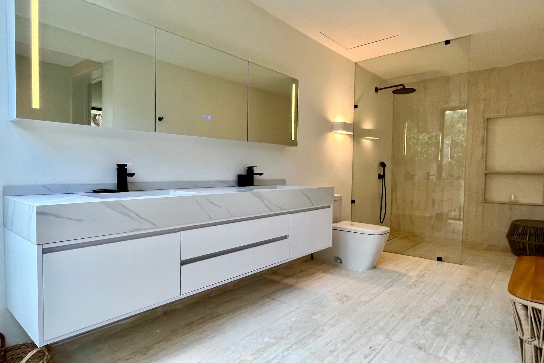 Un baño moderno y luminoso con un lavabo largo y una ducha.