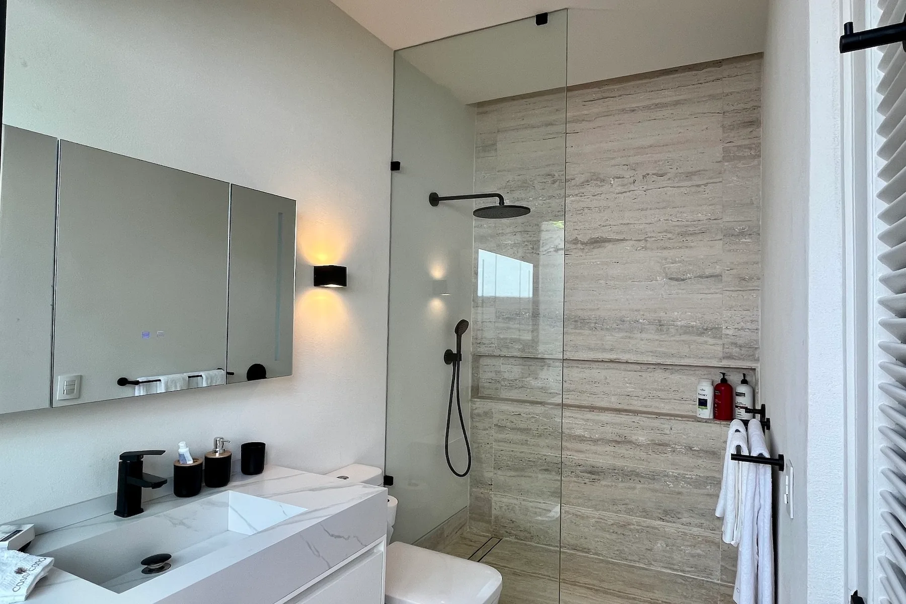 Un baño con lavabo, espejo y ducha de vidrio.