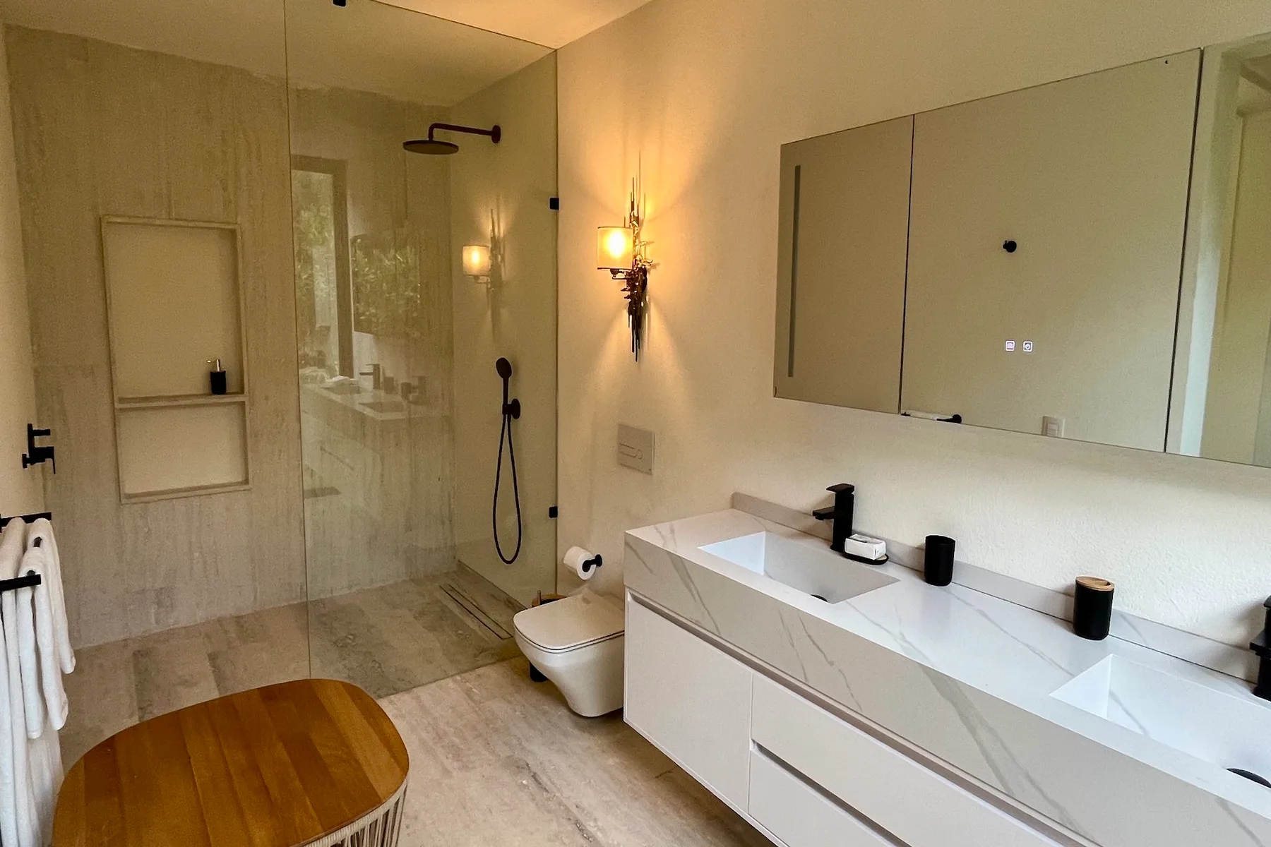 Un baño con una ducha de cristal y un mueble largo con lavabos.