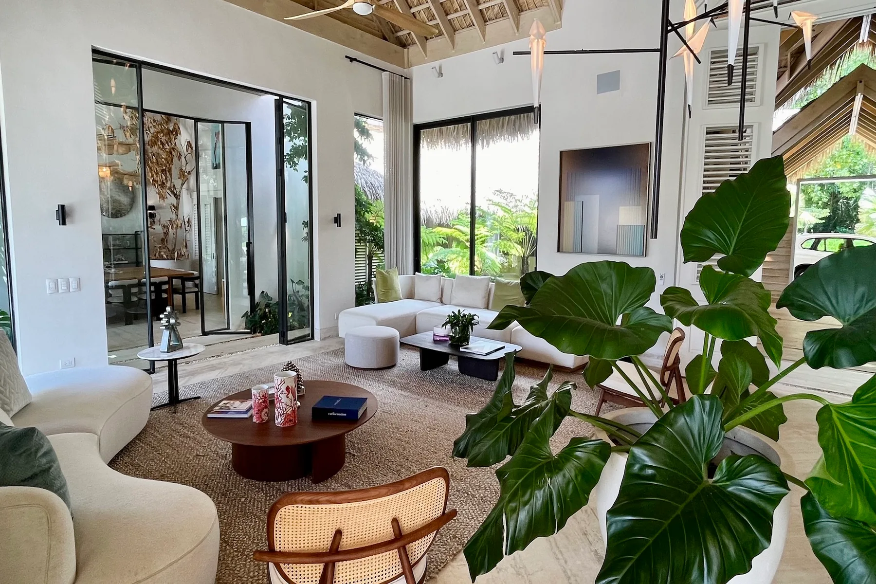 Una sala luminosa con asientos, una mesa baja y plantas de hojas grandes.