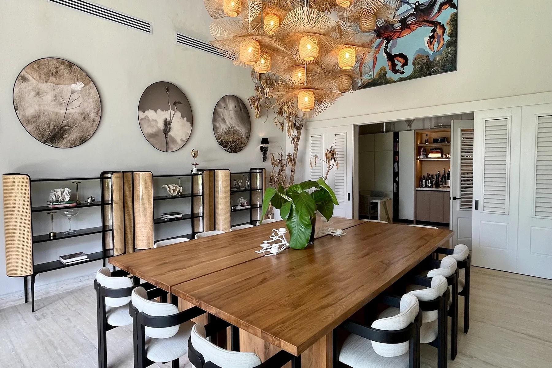 Un comedor con una mesa larga de madera, sillas y una lámpara colgante grande.