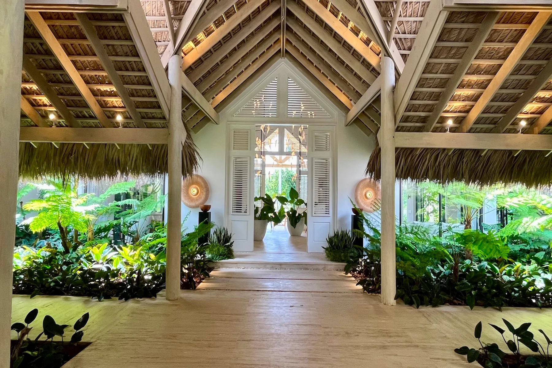Un espacio cubierto y abierto con techo inclinado y vistas a un jardín frondoso.