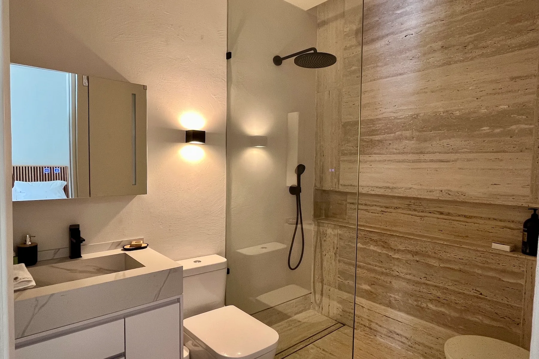 Un baño con tocador, inodoro y ducha con mampara de vidrio.