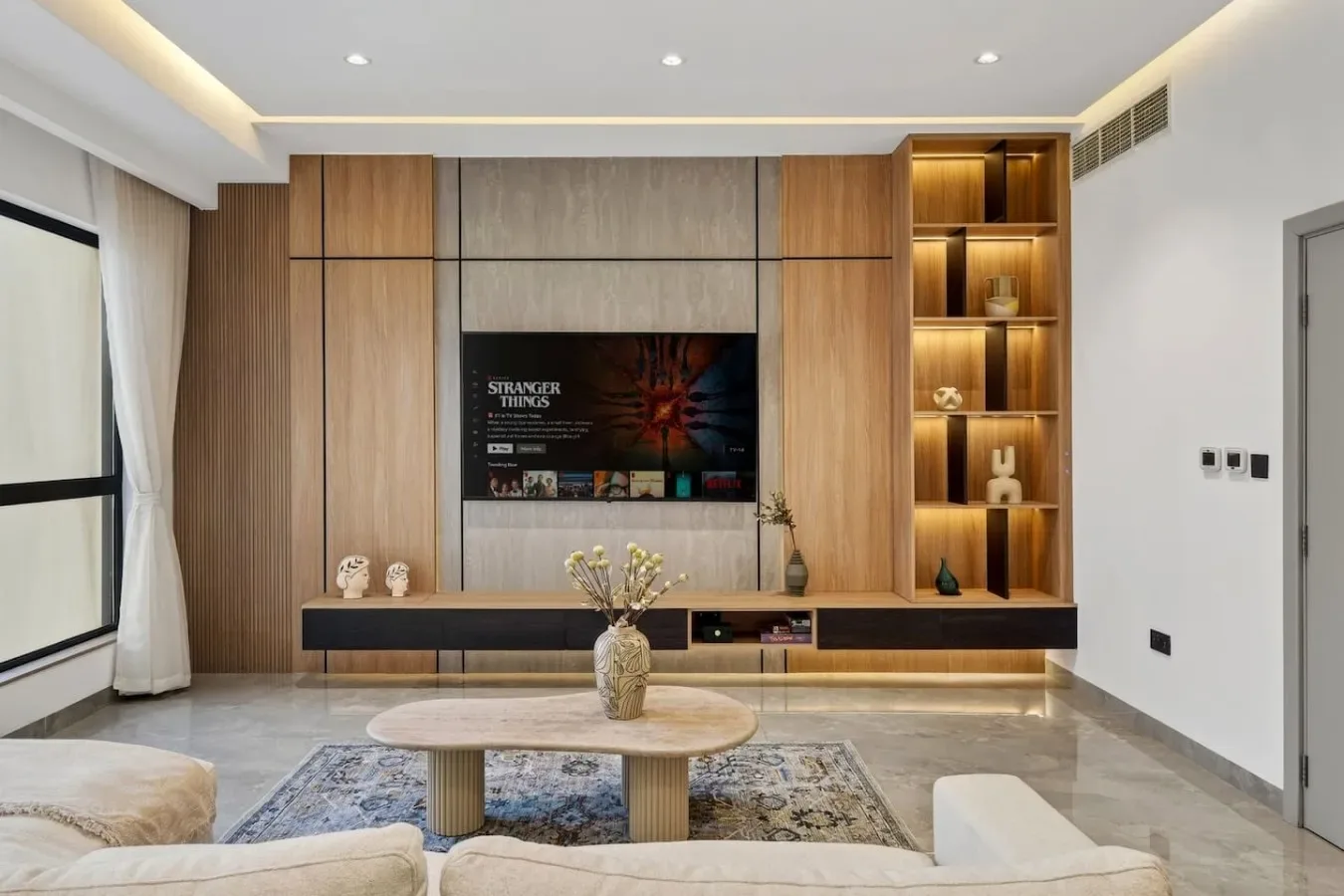 A modern living room with a wall-mounted television and a low coffee table.