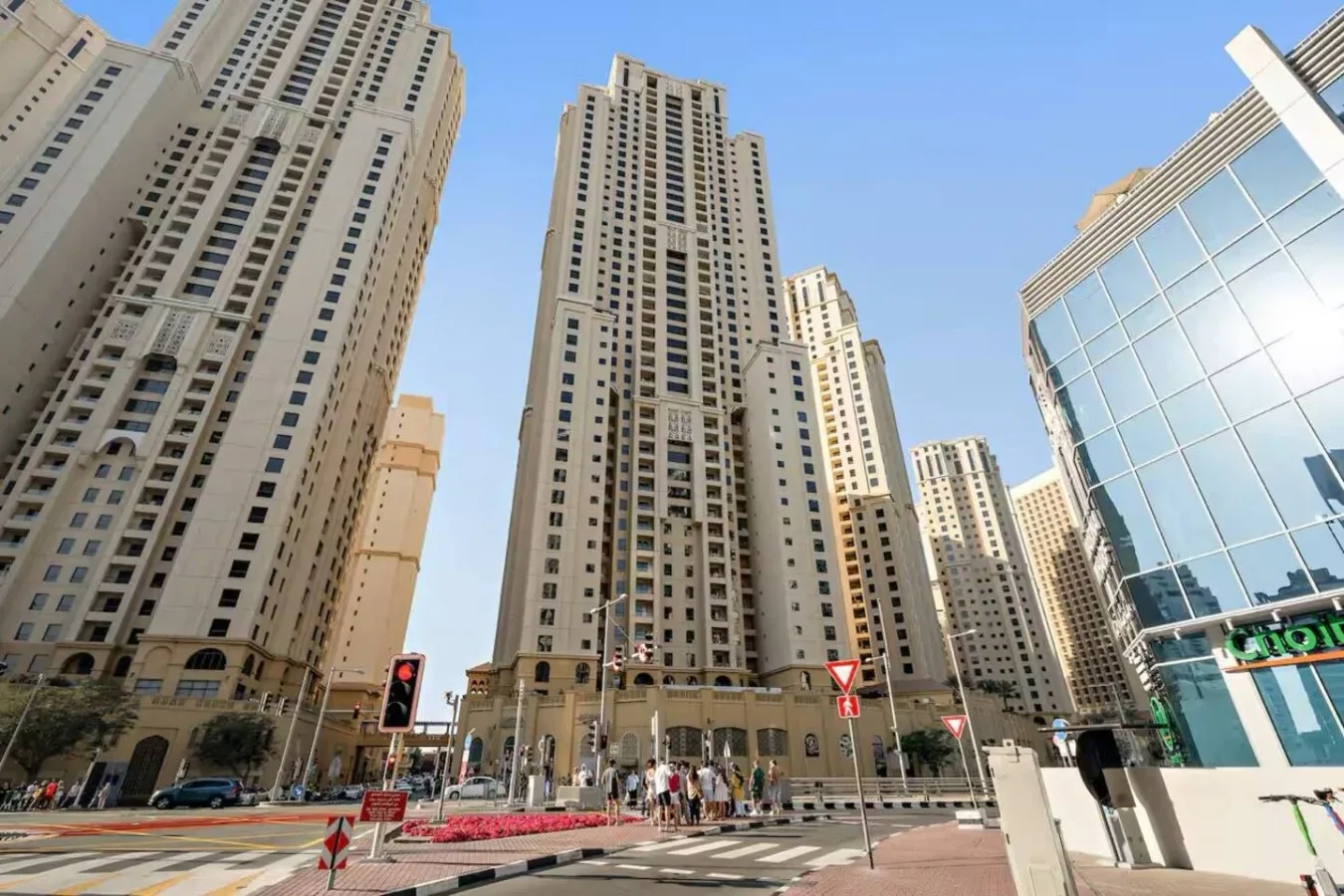 Tall towers line a city street beside a modern glass-fronted building.