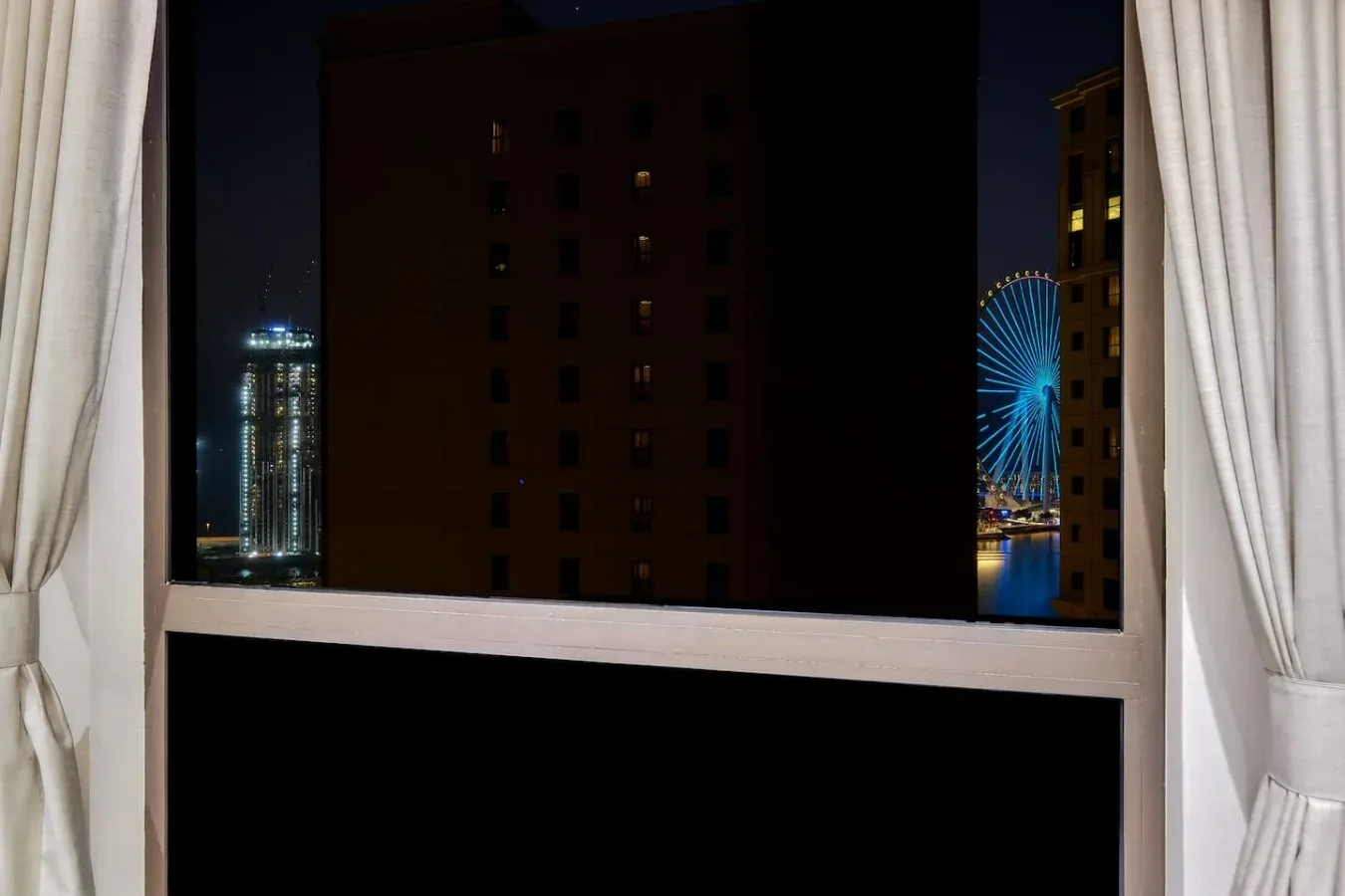 A nighttime city view appears through a window framed by curtains.