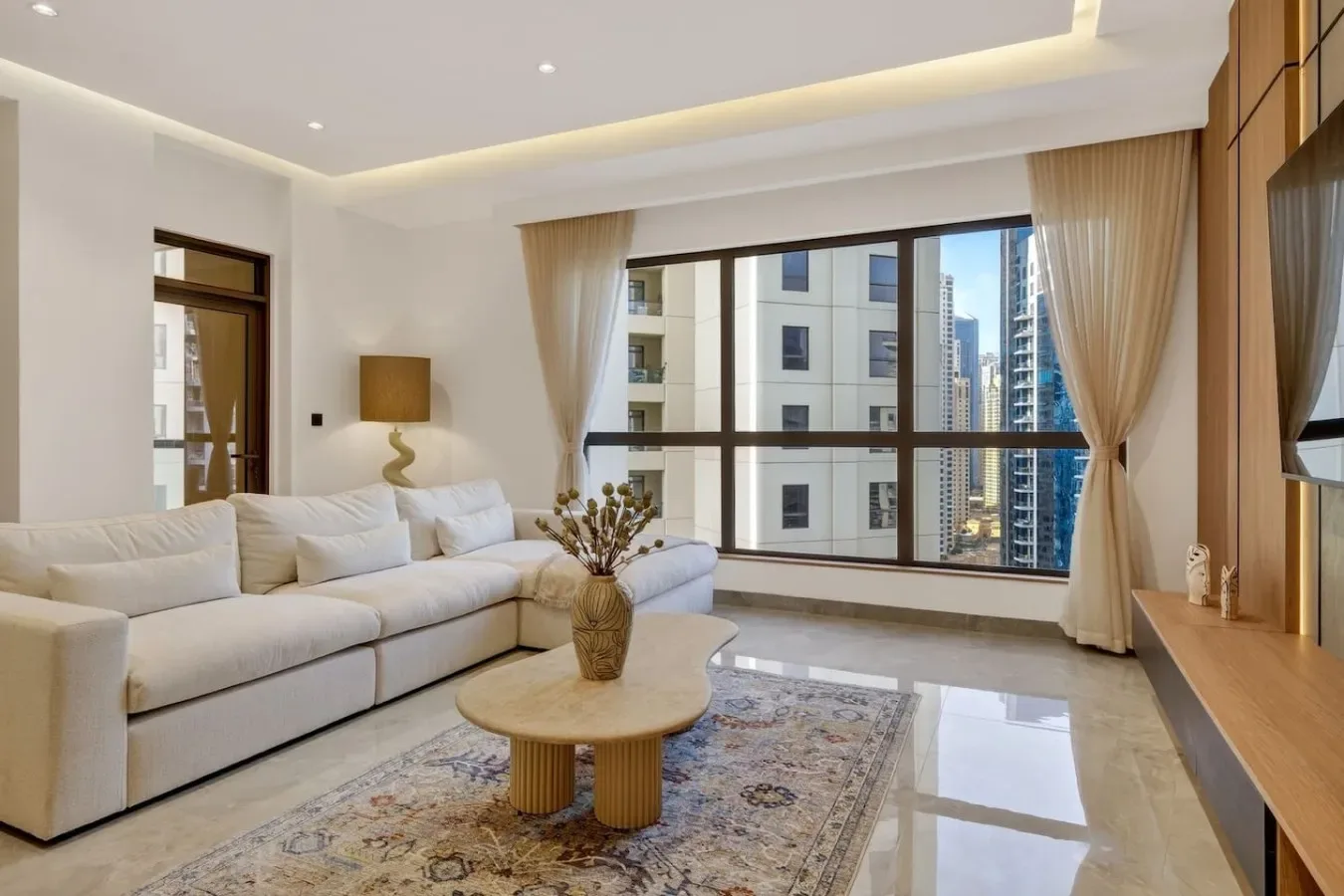 A bright living room with a sectional sofa, coffee table, and large windows.