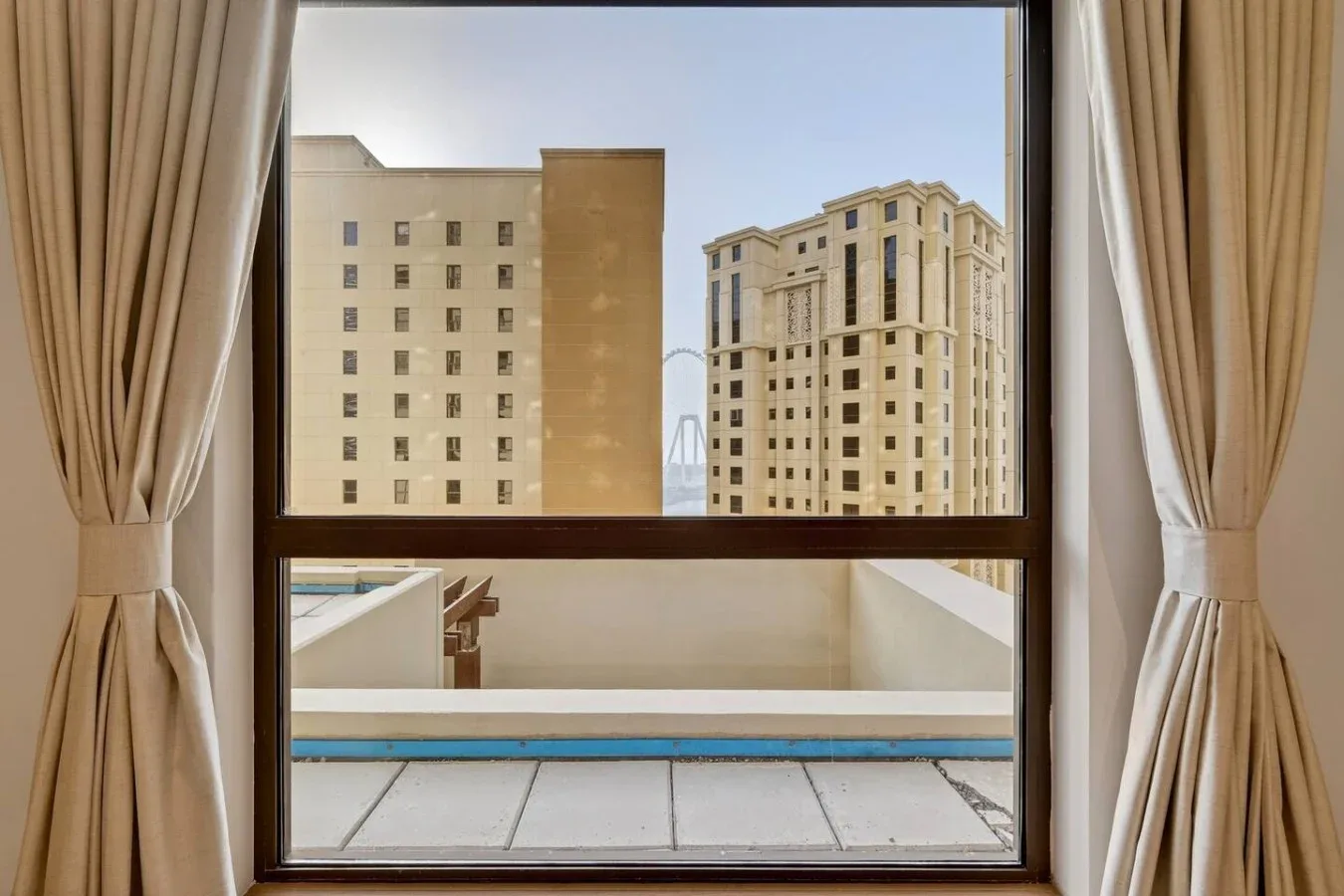 A window overlooks neighboring buildings and a balcony.