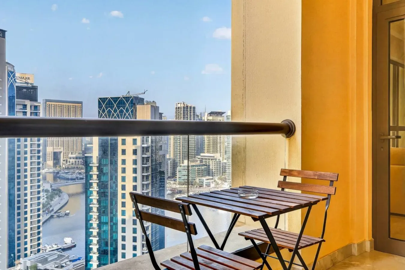 A balcony seating area overlooks a city skyline and canal.