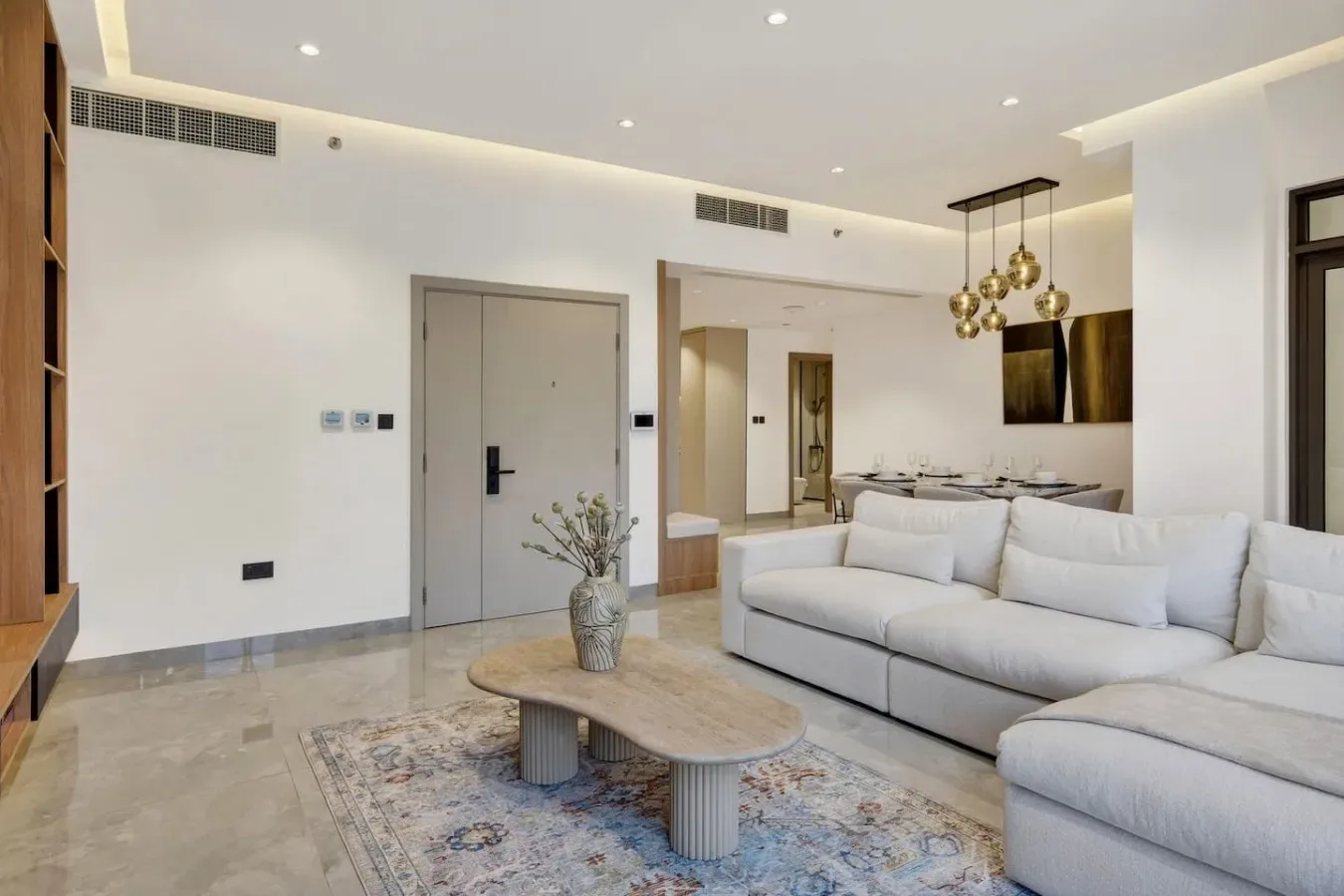 A bright living room with a light-colored sectional and a dining area beyond.