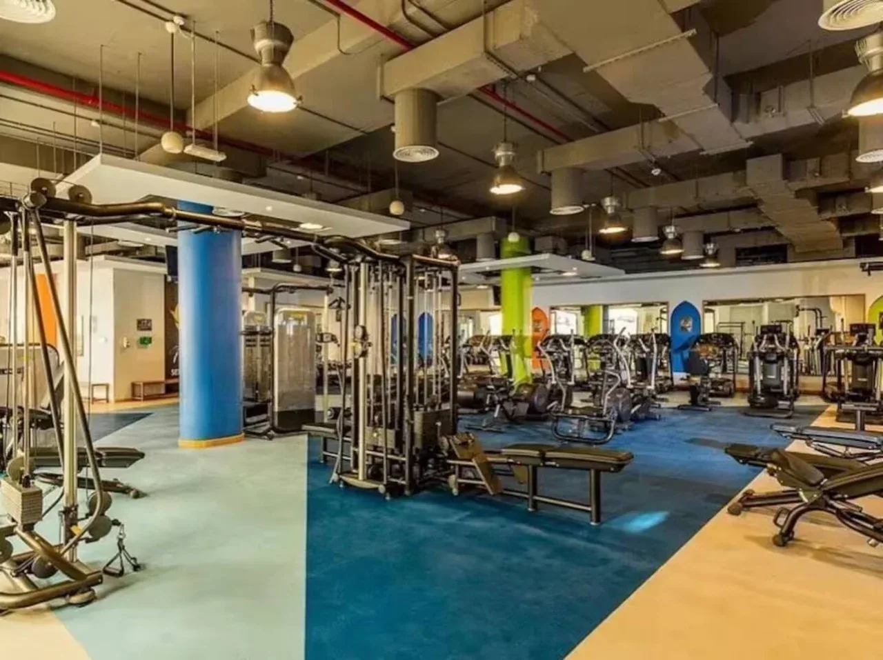 A gym with exercise machines and weight-training equipment across a spacious floor.
