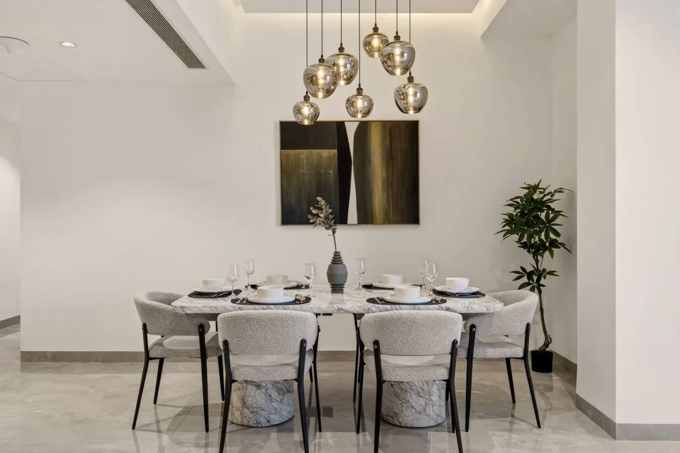 Comedor con una mesa preparada para comer bajo lámparas colgantes.
