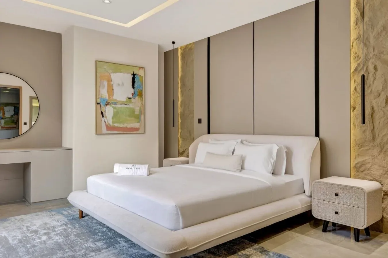 A bedroom with a bed, bedside table, and abstract wall art.
