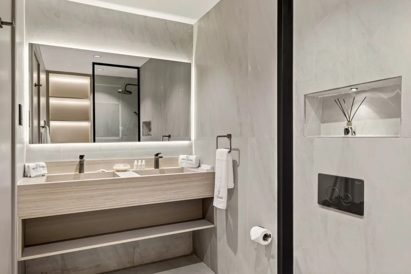 A modern bathroom vanity with a wide mirror and wall-mounted fixtures.