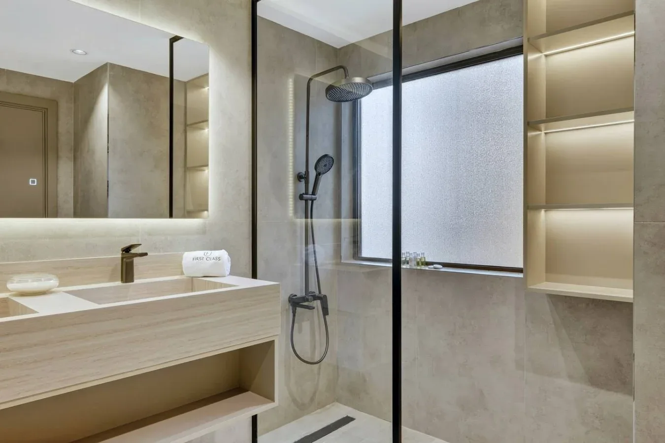 A modern bathroom with a sink vanity, shower, and large frosted window.
