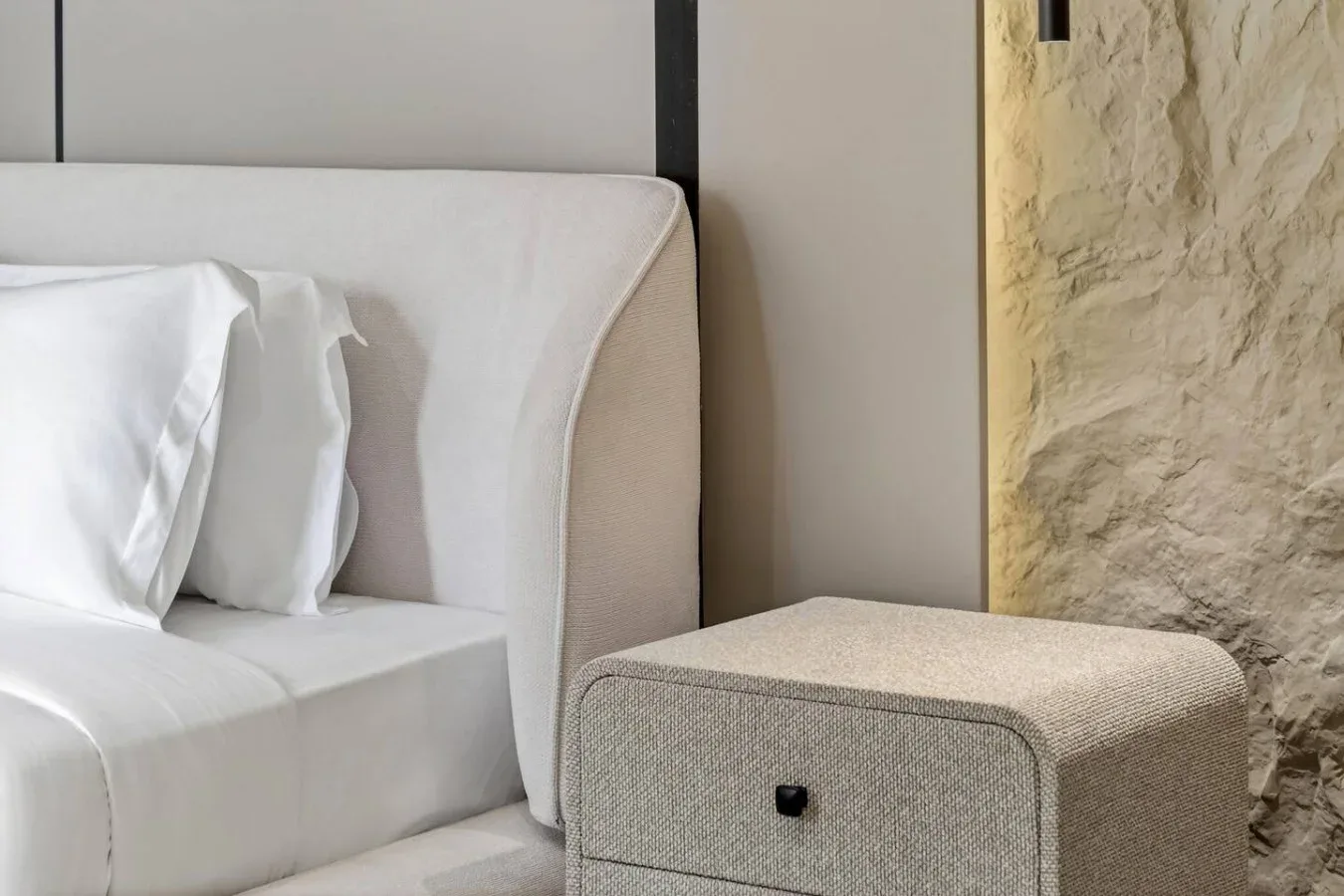 A bedroom seating area with a bed and a small upholstered stool.