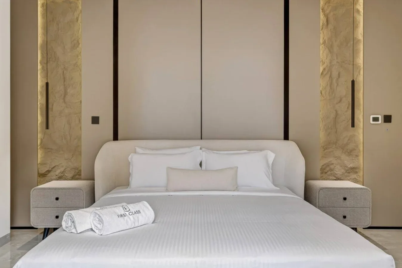A neatly made bedroom features a bed with white linens and matching bedside tables.
