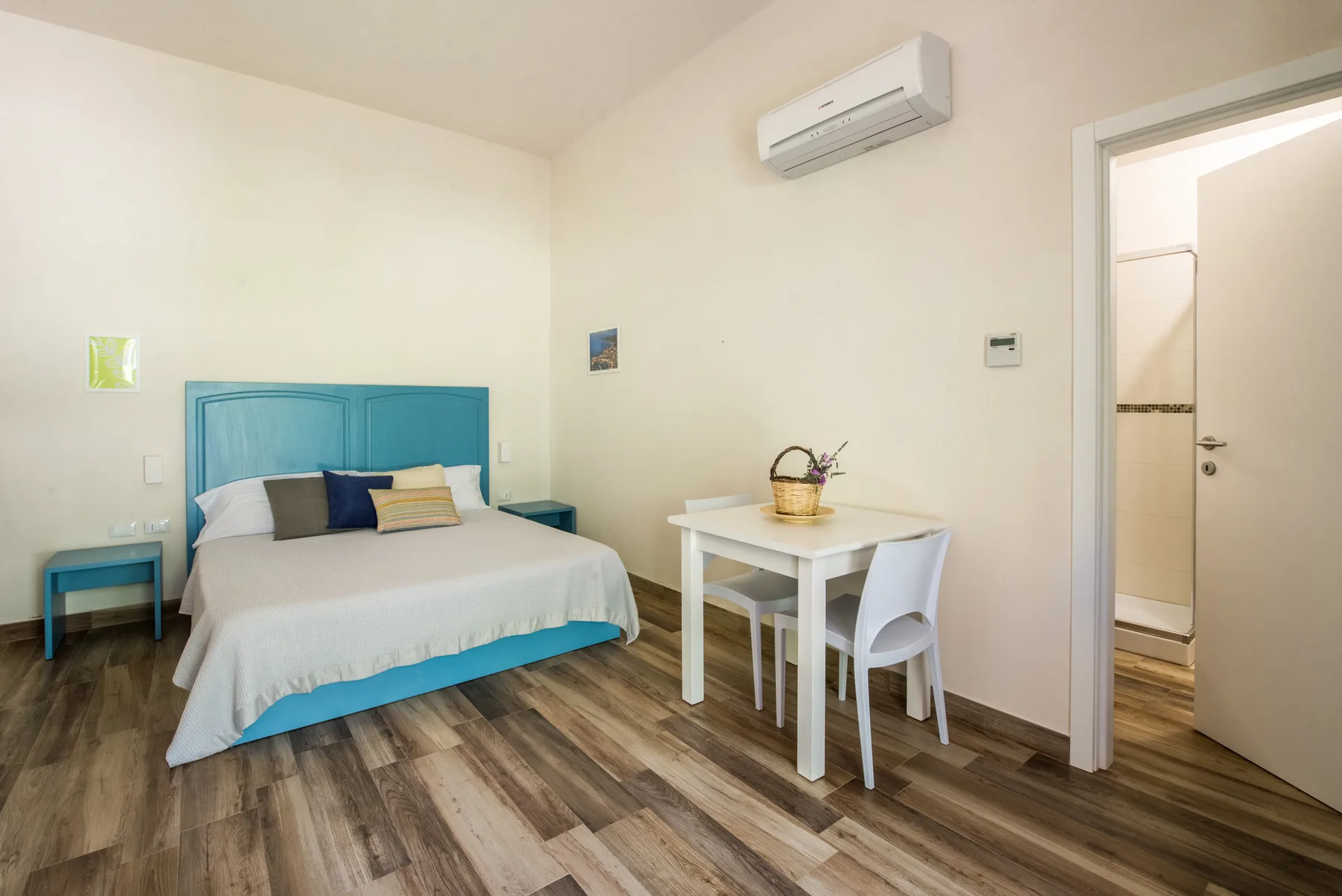 A bedroom with a blue bed and a small table beside it.