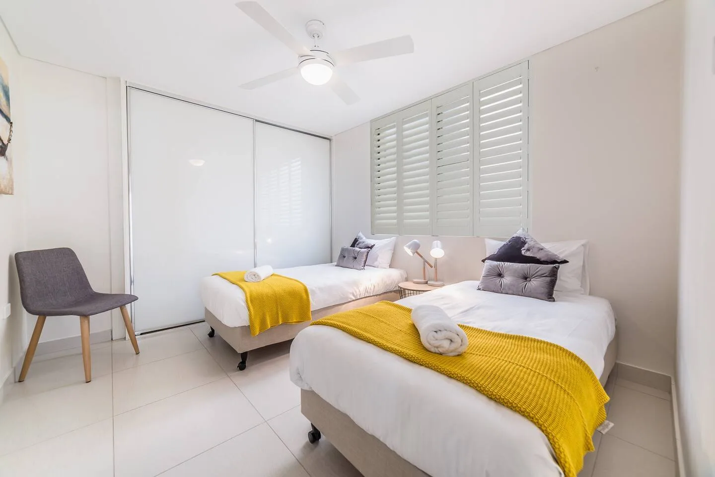 Un dormitorio con dos camas, colchas amarillas y una silla.