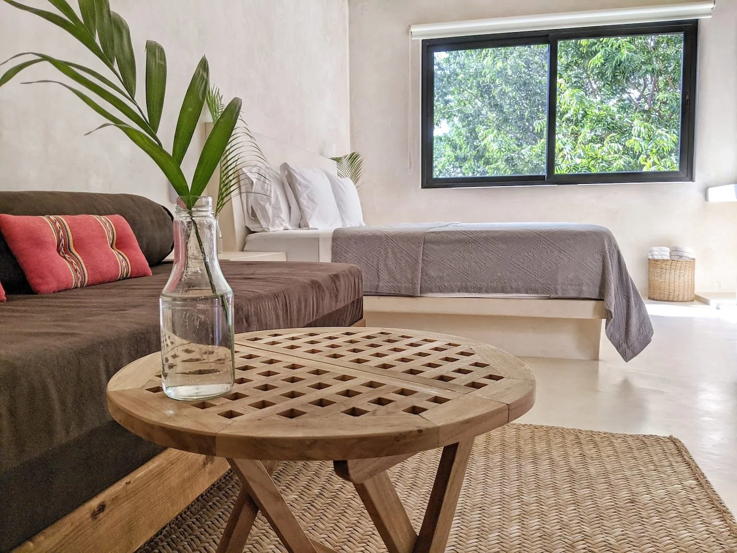 Un dormitorio luminoso con una cama, asientos y una mesa redonda de madera.