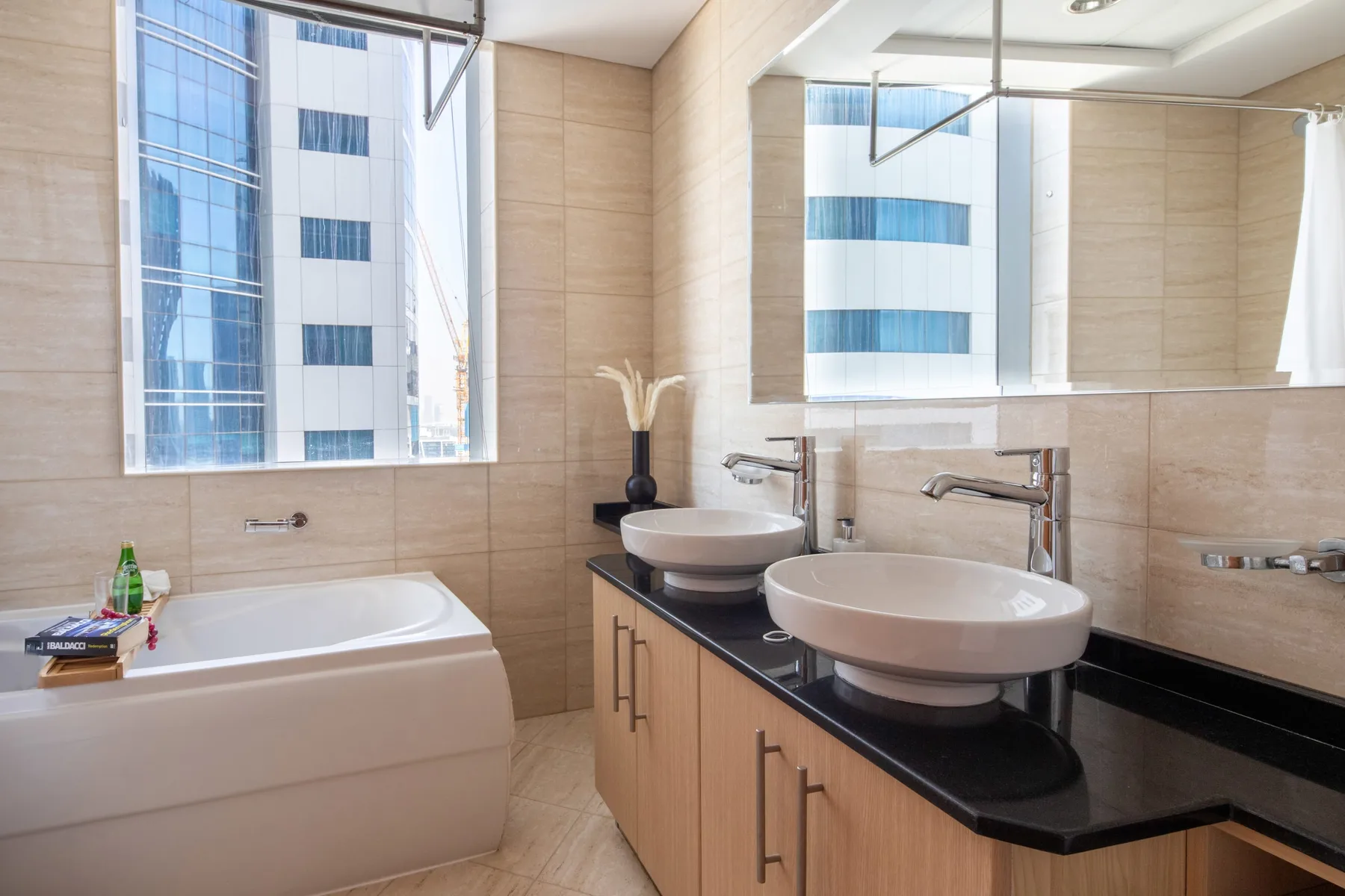Un baño luminoso con bañera, dos lavabos sobre encimera y ventanas grandes.