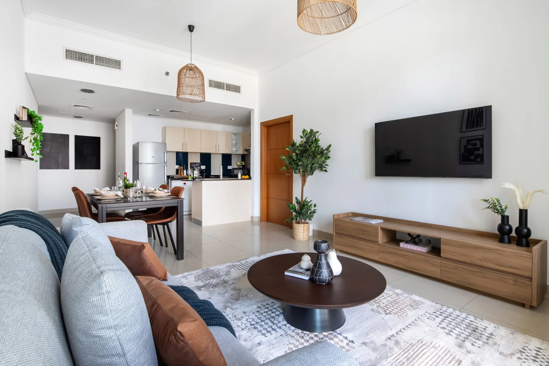 Una luminosa sala-comedor con sofá, televisor y cocina abierta.