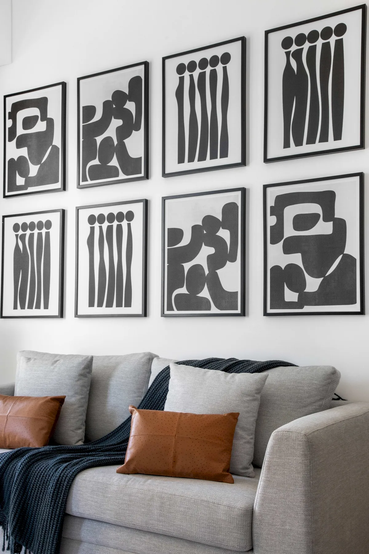 Una zona de estar con láminas abstractas en blanco y negro sobre el sofá.