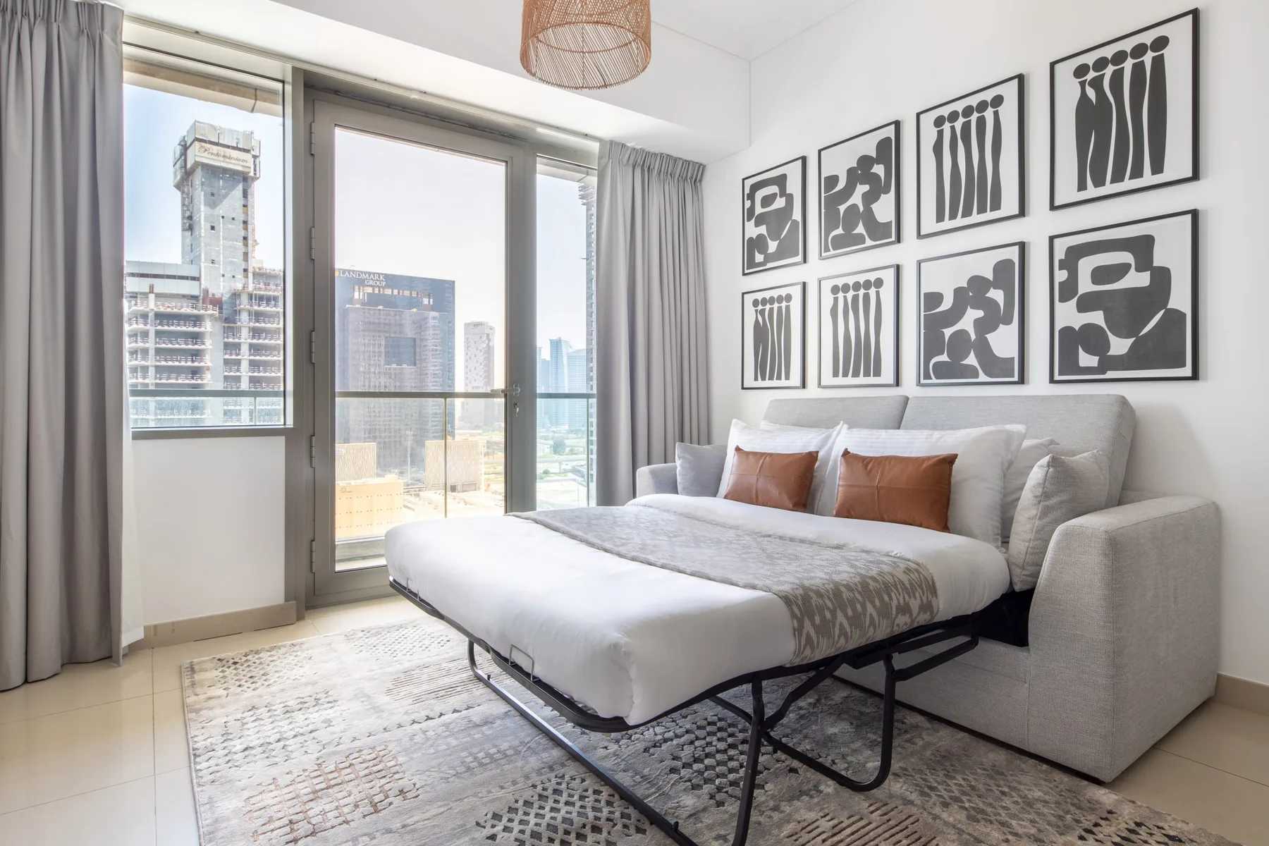 Un dormitorio luminoso con una cama grande, vistas a la ciudad y cuadros enmarcados.