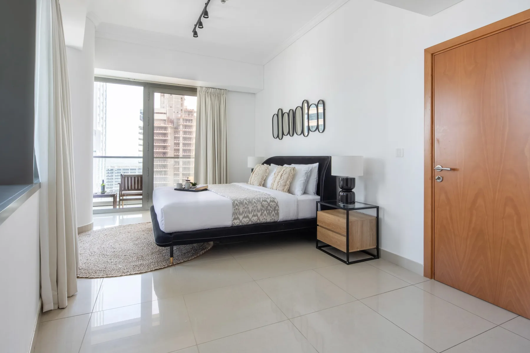 Un dormitorio luminoso con una cama, una mesita de noche y puertas corredizas de vidrio.