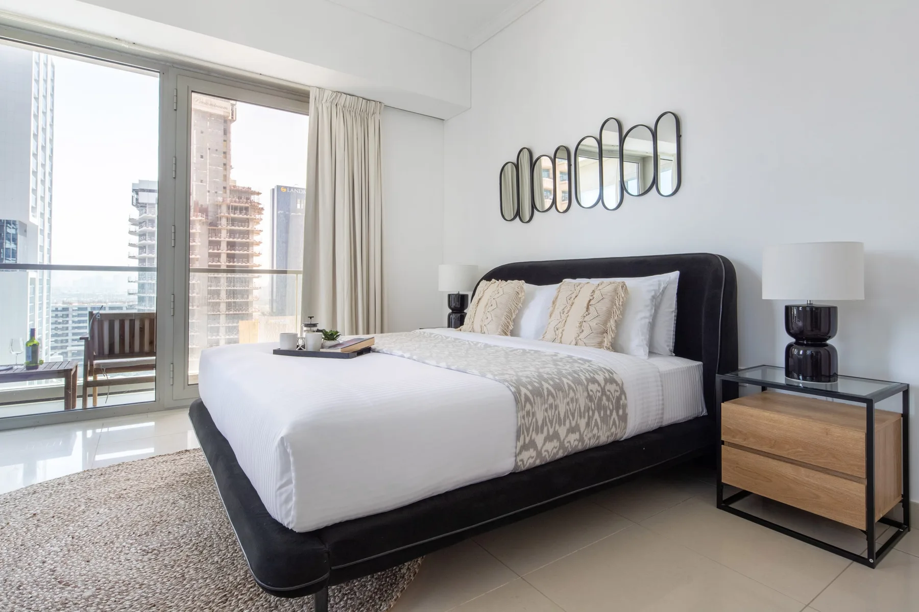 Un dormitorio luminoso con una cama tendida junto a una ventana grande.