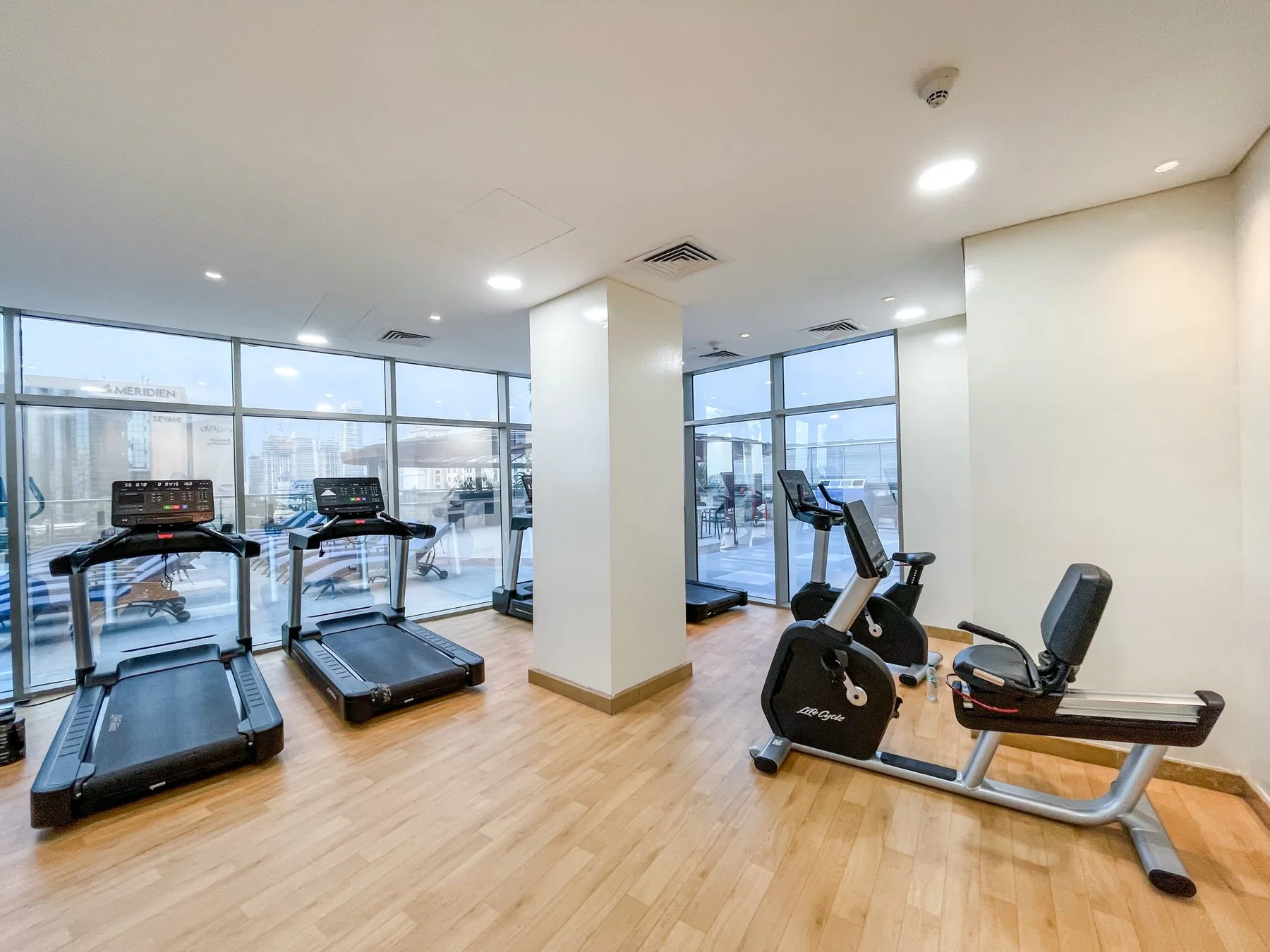 Una sala de ejercicios luminosa con cintas de correr y equipos de ejercicio estacionario.