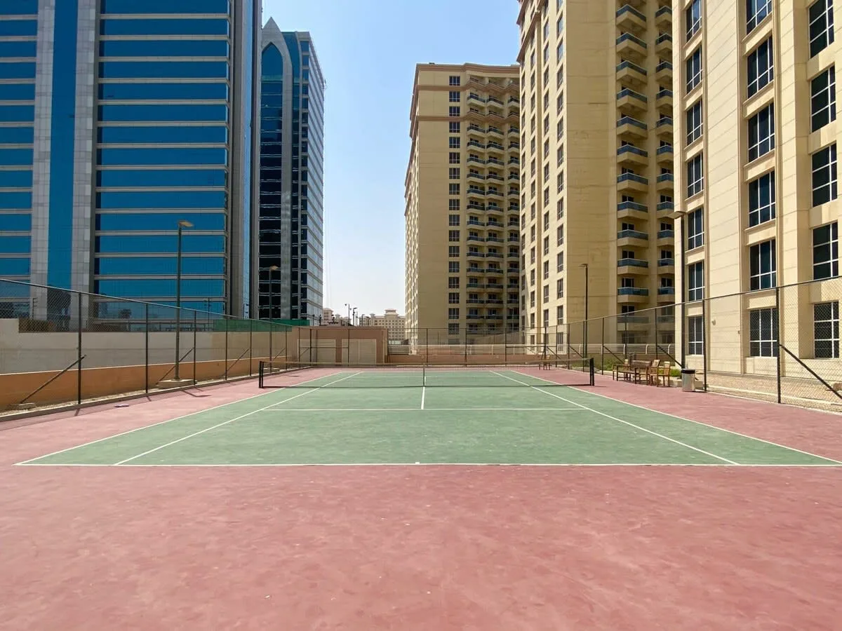 Una cancha de tenis al aire libre está entre edificios altos.