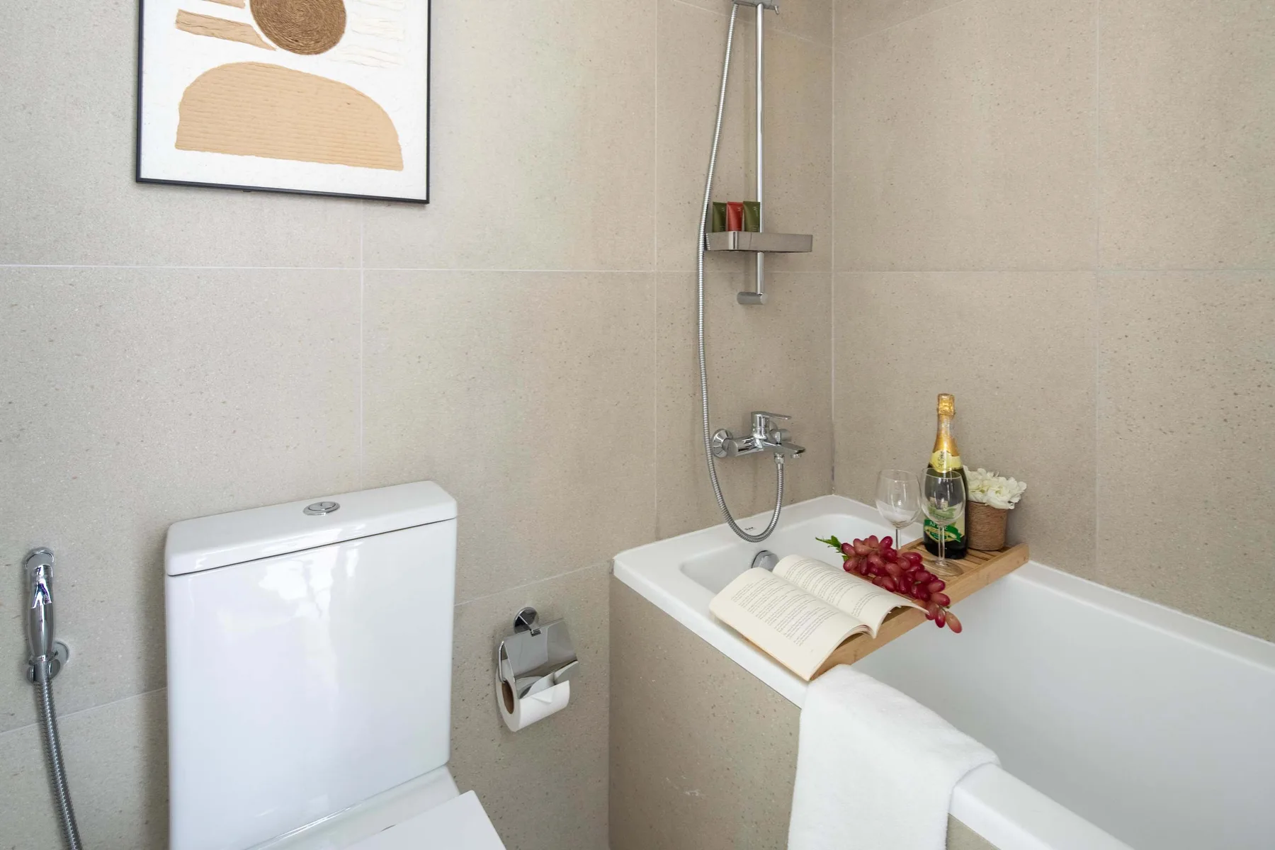 Un baño alicatado con bañera, ducha y un libro abierto.