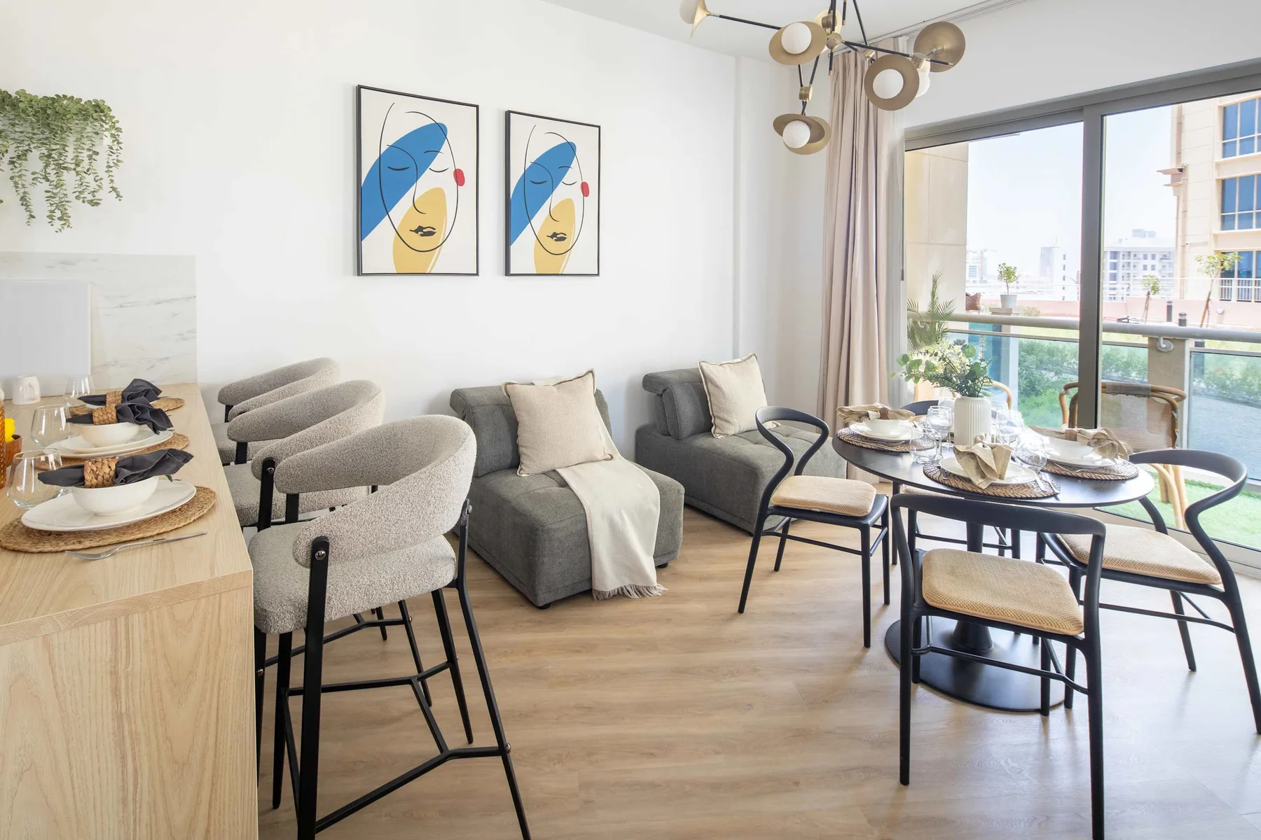Una luminosa sala de estar y comedor con asientos, una mesa puesta y grandes ventanales.