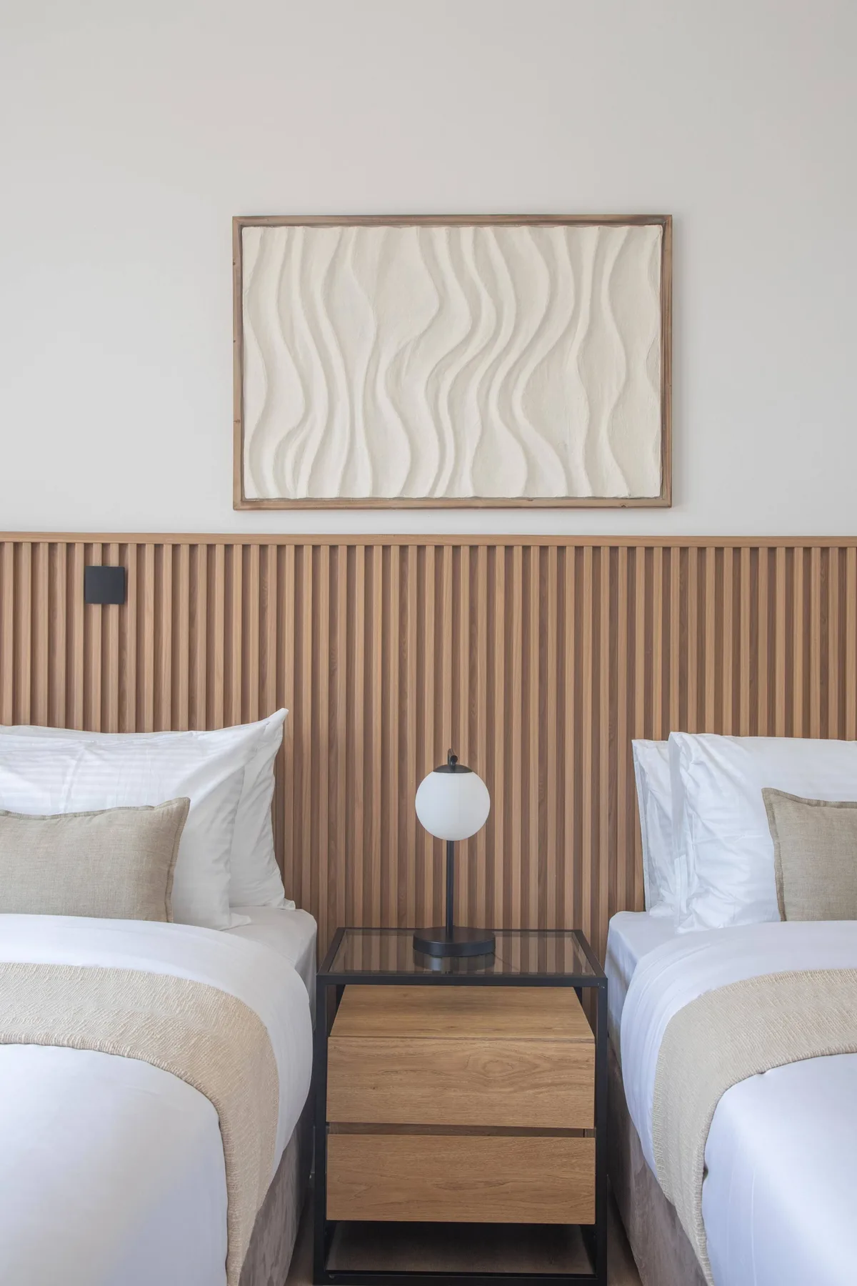 Un dormitorio con dos camas, una mesita de noche y arte enmarcado en la pared.
