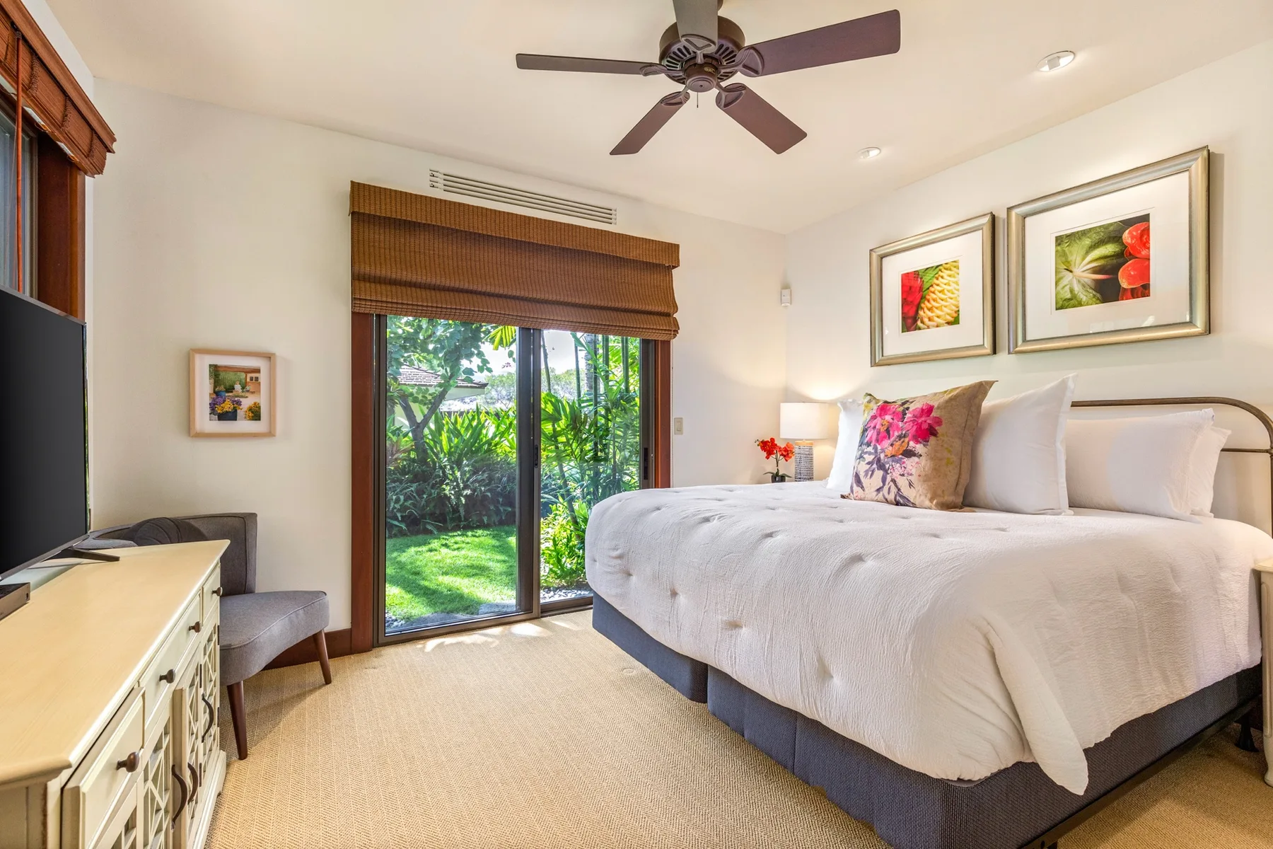 A bedroom with a neatly made bed and sliding glass doors overlooking greenery.