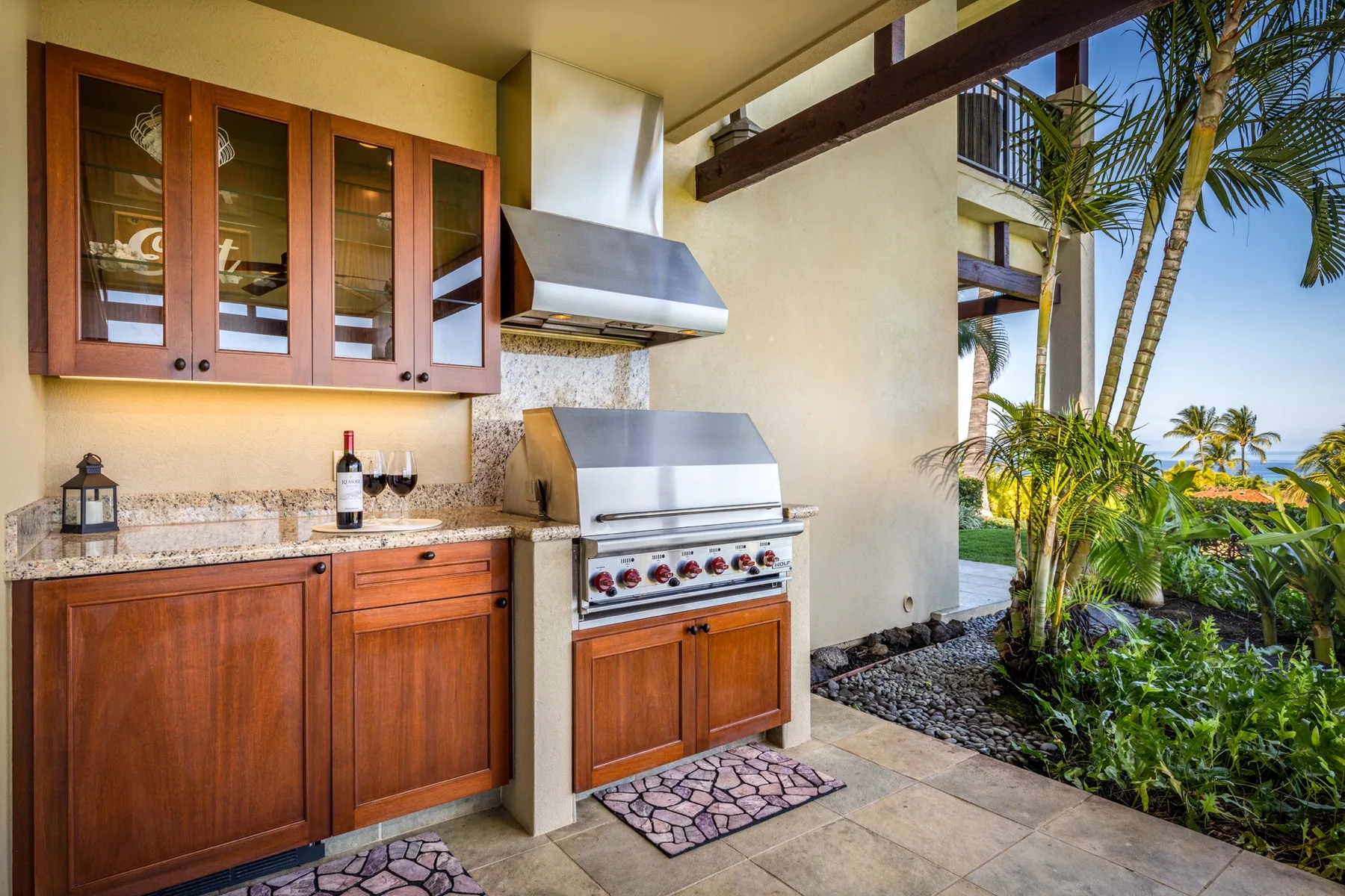 An outdoor kitchen with wooden cabinets, a countertop, and a stainless-steel grill.