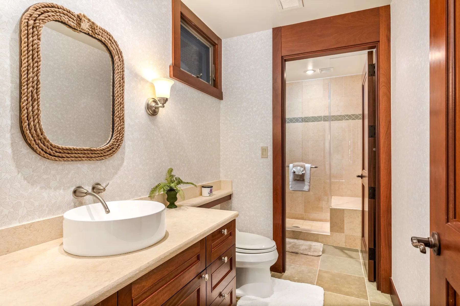 A bathroom vanity with a vessel sink and mirror sits beside an open doorway to the shower.