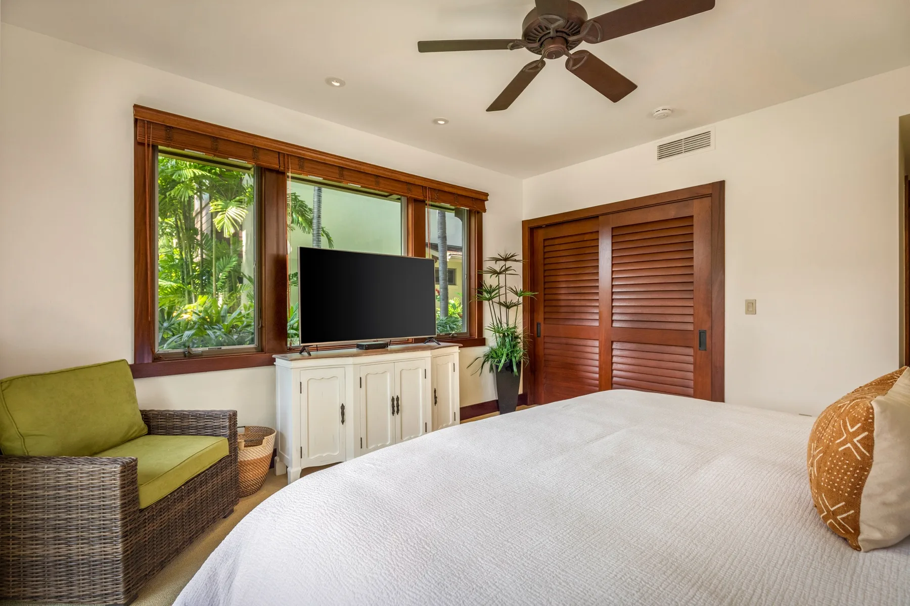 A bedroom with a bed, a window, and wooden louvered doors.