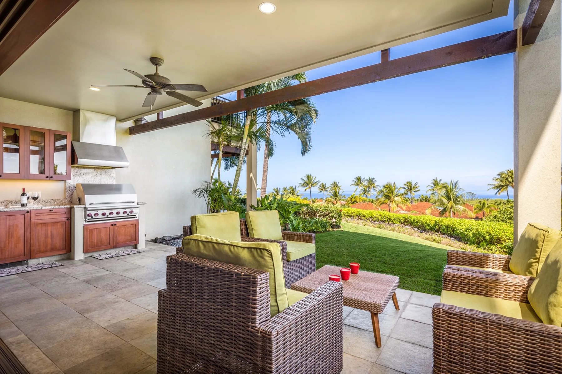 A covered outdoor seating area overlooks a landscaped garden and ocean.