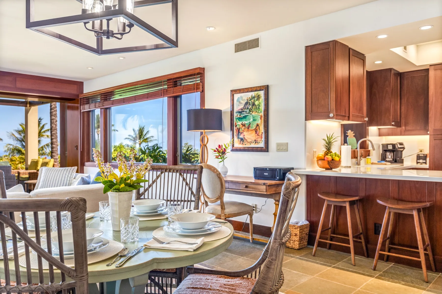 A dining area with a set table beside a kitchen and large windows.