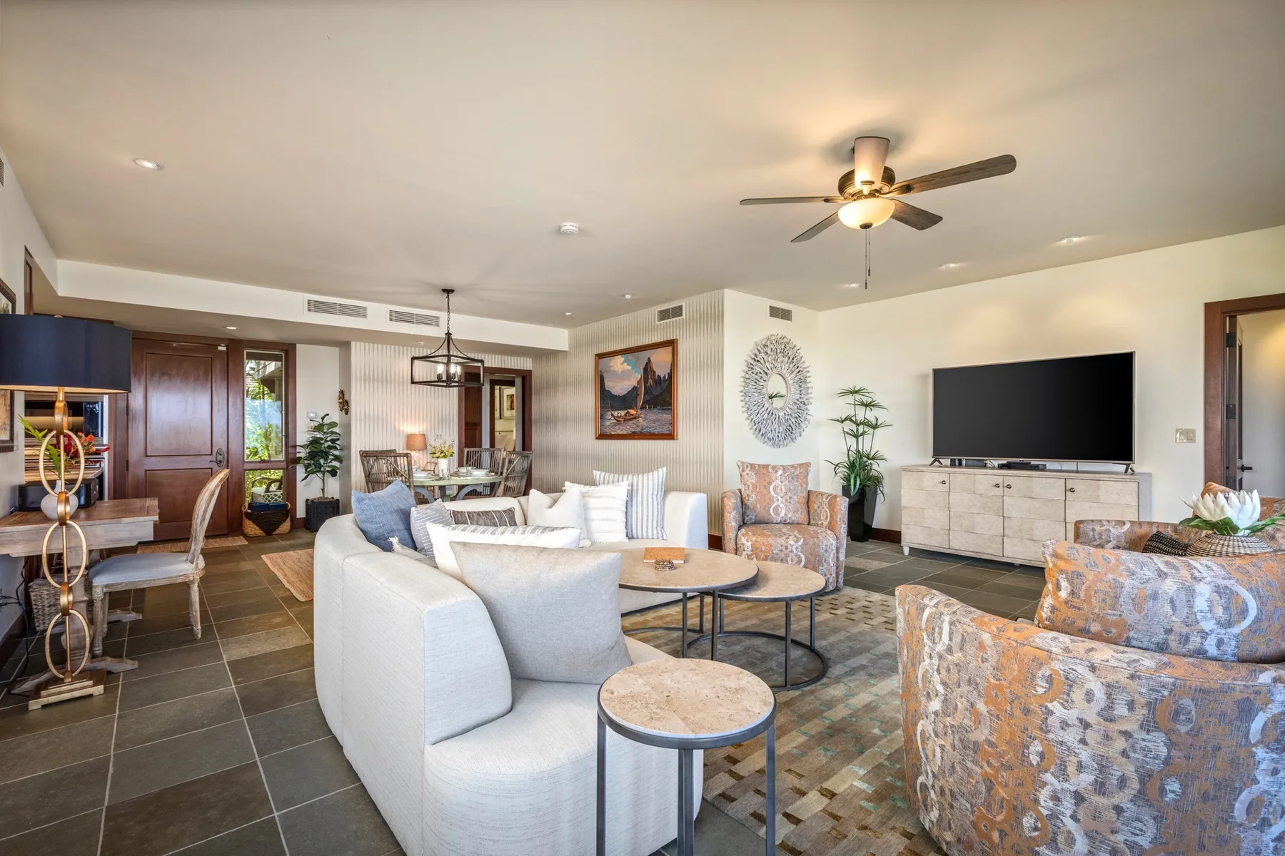 A living room with seating arranged around a coffee table and television.