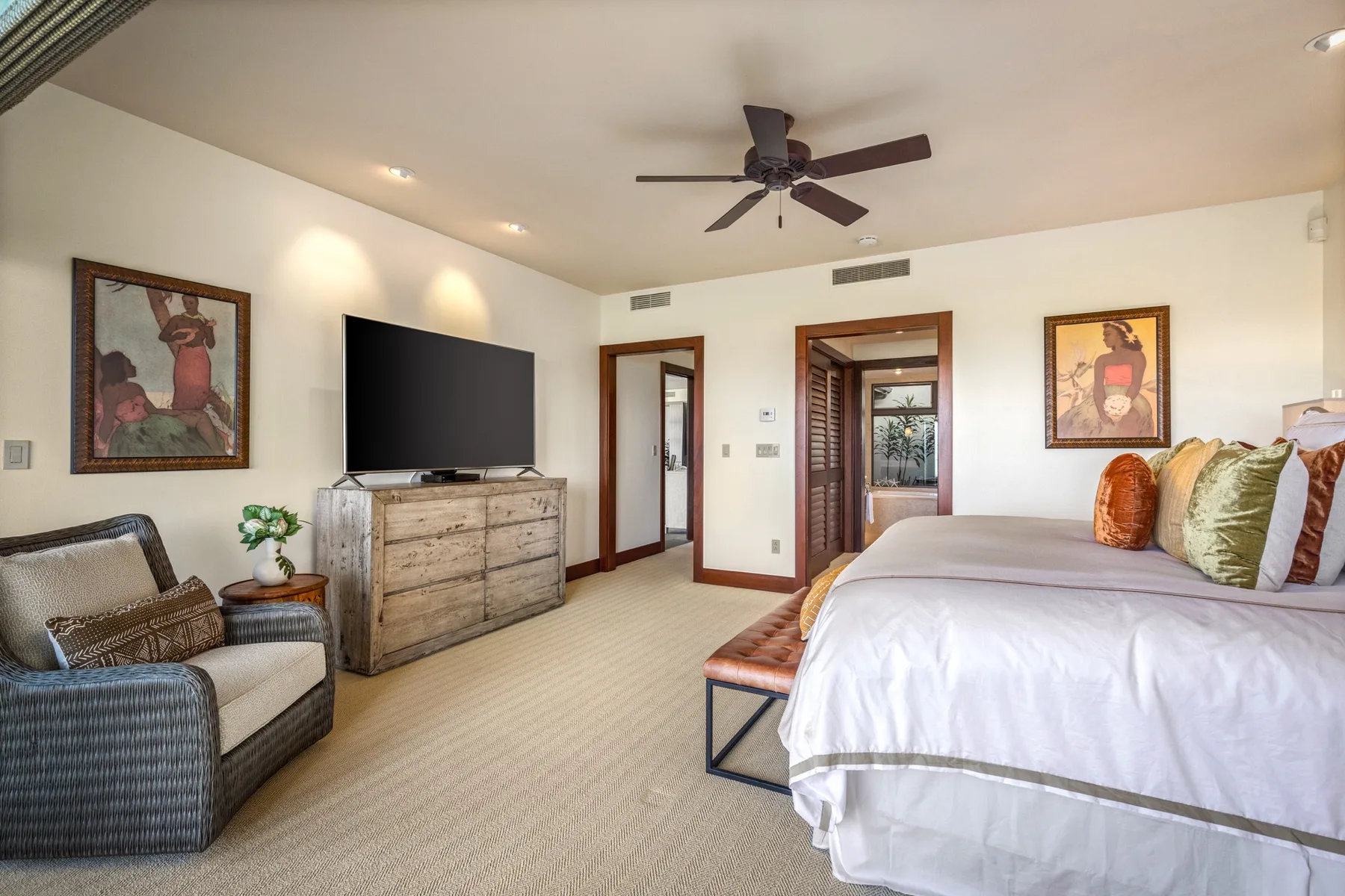A bedroom with a large bed, a television, and a ceiling fan.
