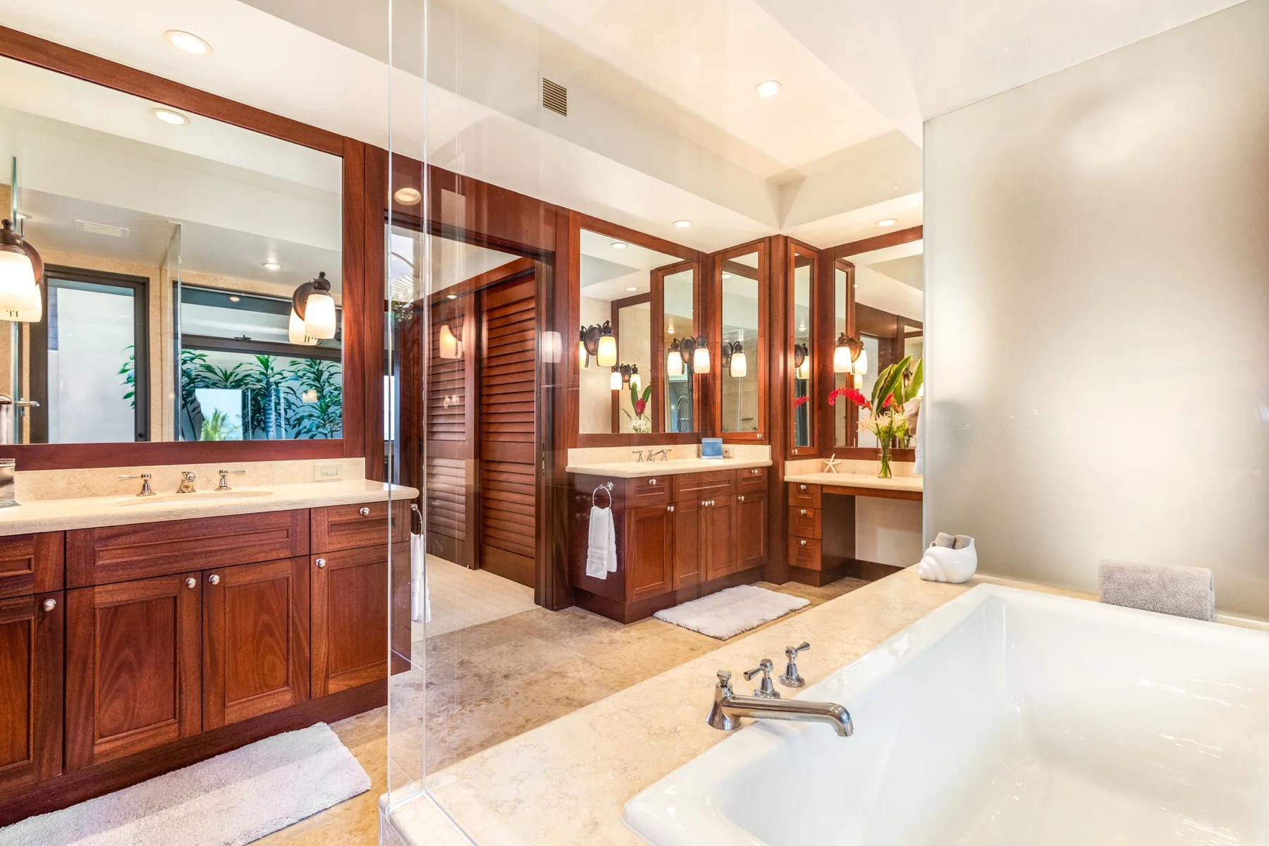 A spacious bathroom features wooden vanities, large mirrors, and a bathtub.