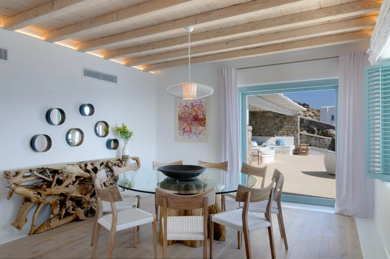 A bright dining area with a glass table and an open view to the terrace.