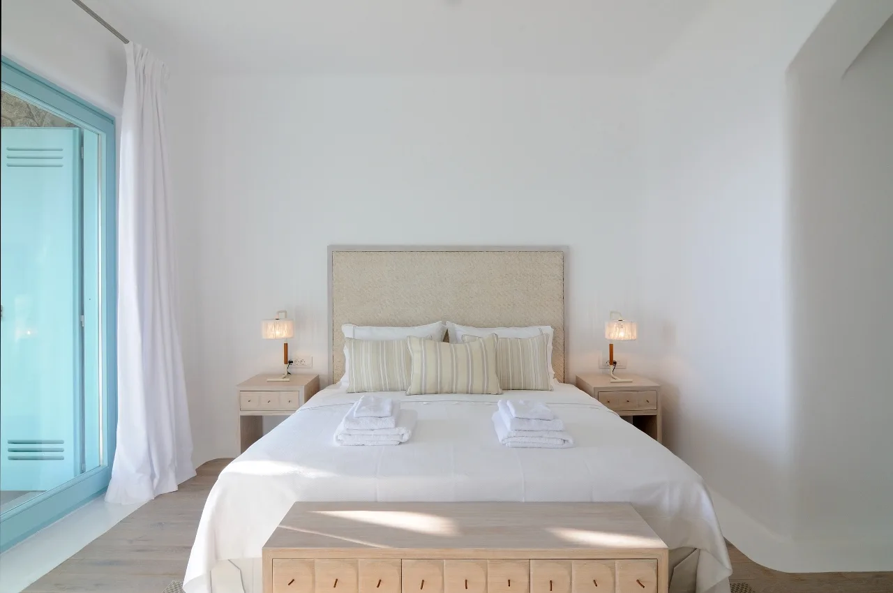 A bright bedroom with a neatly made bed and bedside tables.