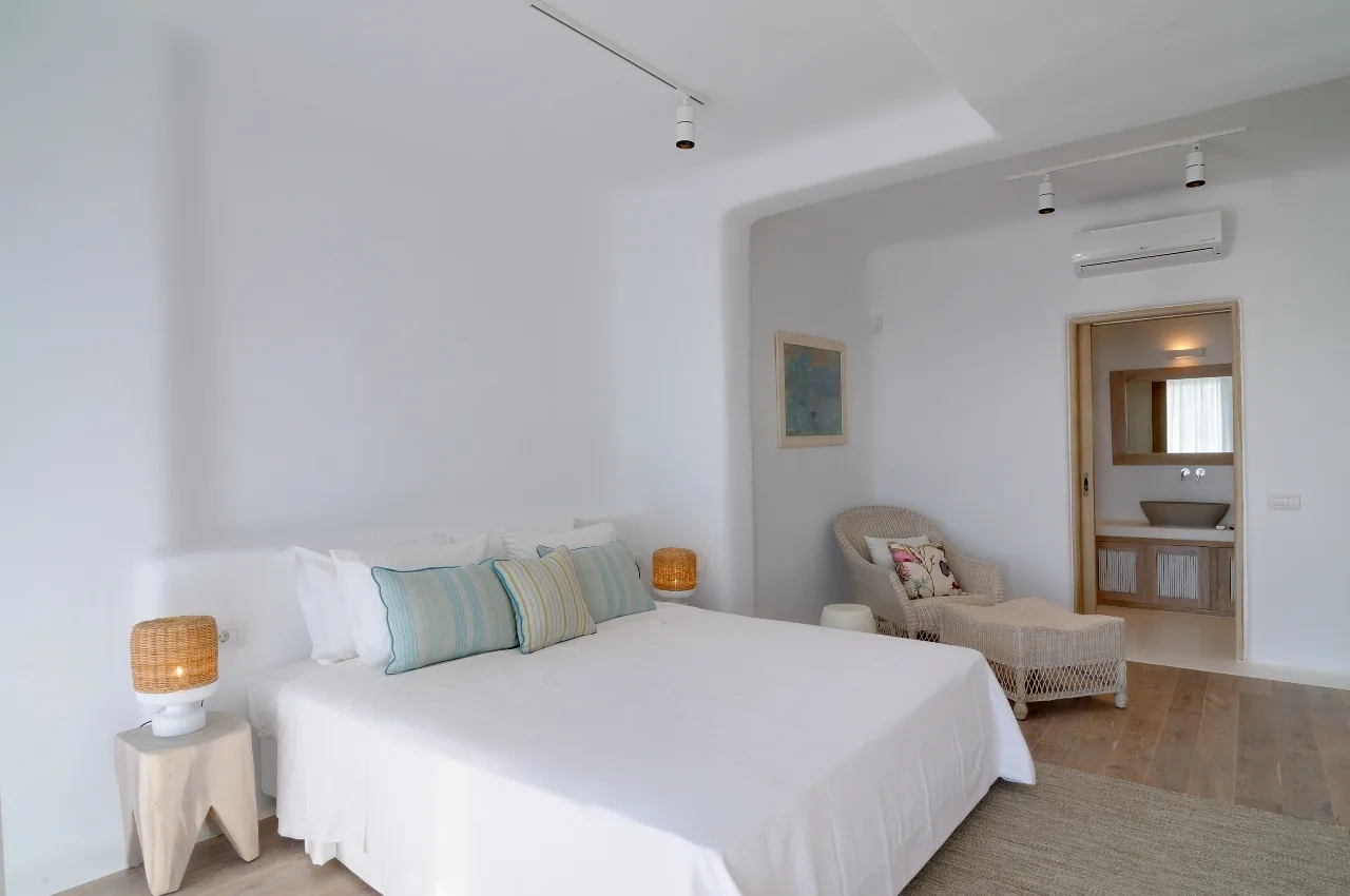 A bright bedroom with a large bed and a small seating area.